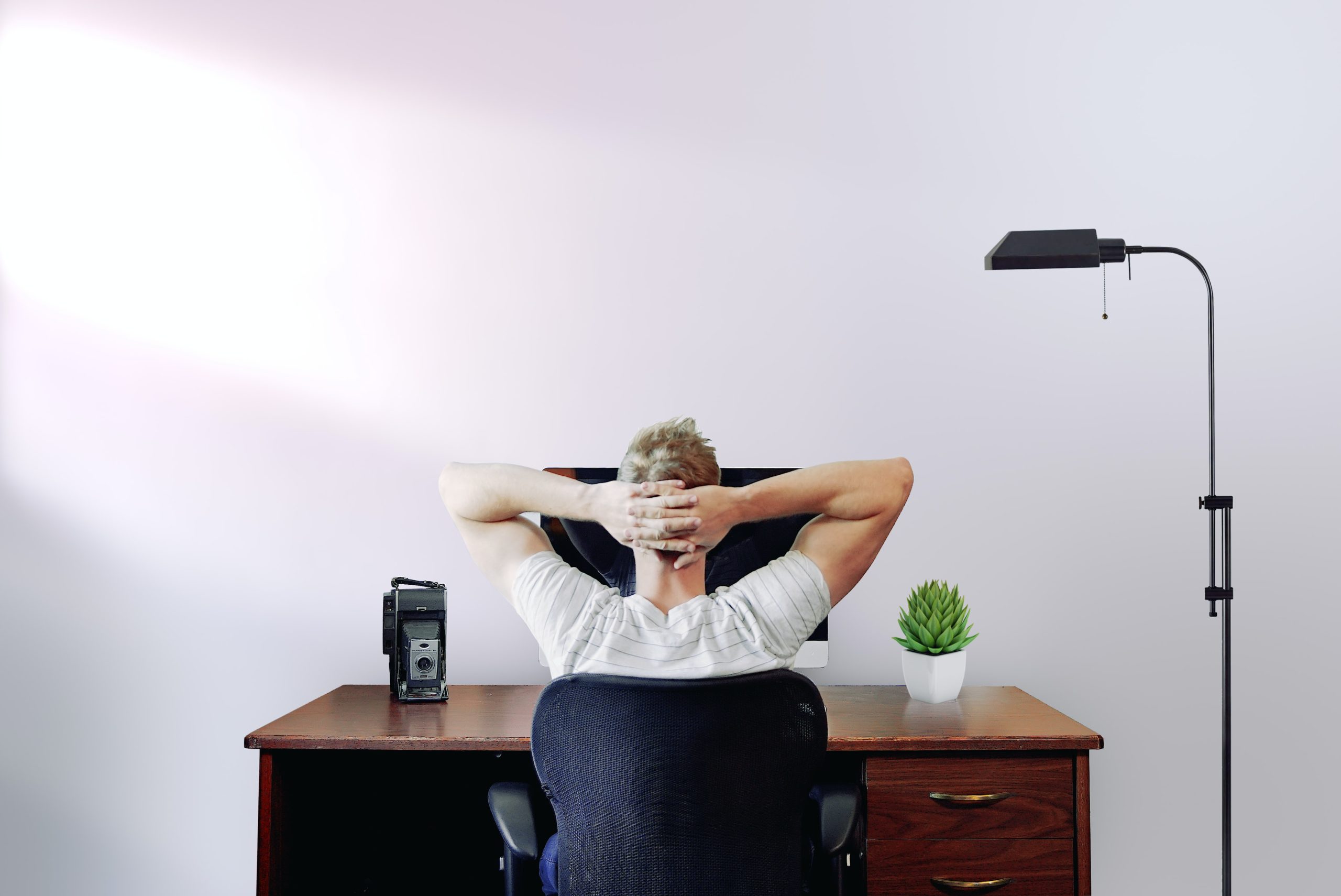 person sitting in front of computer with their hand on their head in a relaxed position